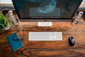 silver iMac near keyboard, mouse, and eyeglasses