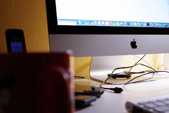 Silver Imac Turned on Beside Red Ceramic Cup