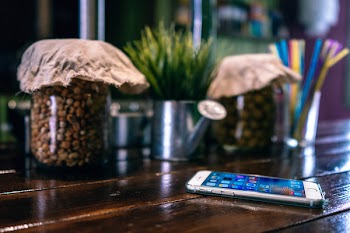 Silver Iphone 6 on Brown Wooden Table Near Jars