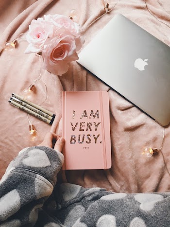 Silver Macbook Beside Planner and Flowers