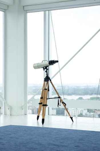 silver telescope beside glass window
