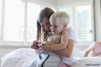 Sister and brother using smart phone on bed