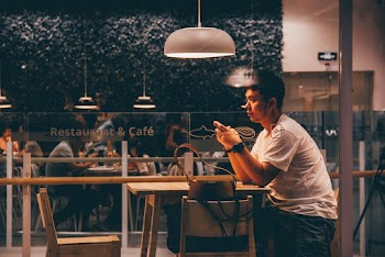 Sitting Man Inside Building Under Pendant Lamp