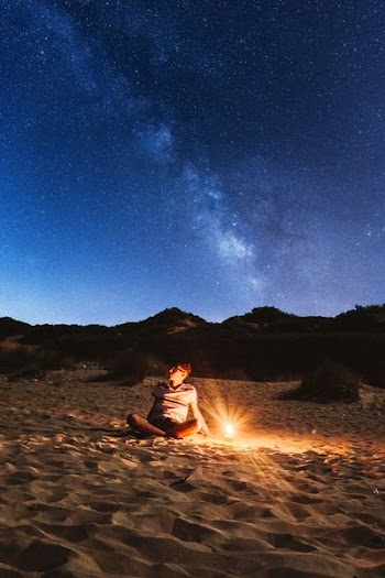 sitting man near lamp looking on the sky with milky way