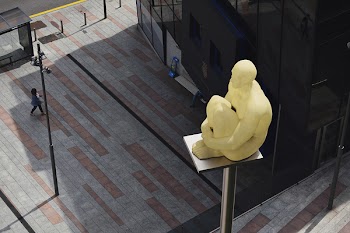 Sitting Man Statue Placed on Gray Metal Post