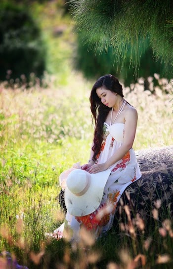 Sitting Woman Puts Her White Sun Hat on Her Lap While Holding It