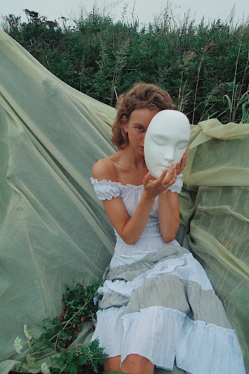 Sitting Woman Wearing Gray Off-shoulder Dress Holding Mask