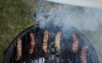 six sausages on black charcoal grill