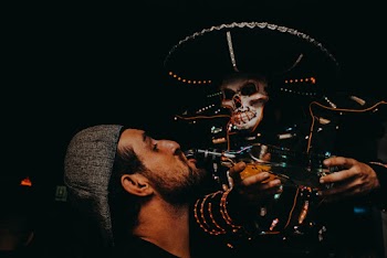 Skeleton Pouring Beverage on Man's Mouth
