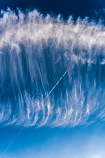 Sky surfing - Airplane skytrail (contrail) in a wave of clouds