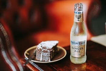 sliced cake on brown saucer beside fever-tree ginger ale bottle