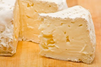 Sliced delicious brie cheese on wooden cutting board