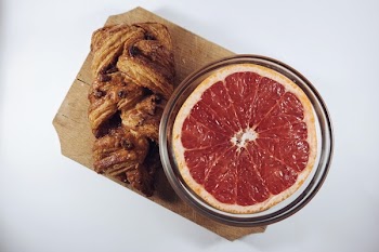 Sliced Orange Fruit in Glass Bowl Beside Baked Bread Both on Brown Wooden Board