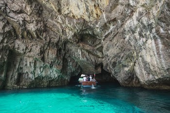 Small Boat Sailing Under Rocks