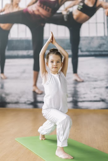 Small innocent girl doing yoga at gym Free Photo