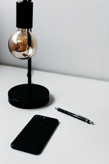 smartphone beside click pen and lamp