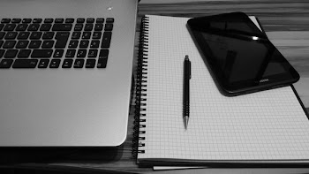 Smartphone Displaying Black Screen Beside Retractable Pen on Grid Notebook