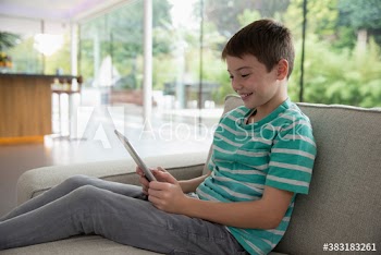 Smiling boy using digital tablet on sofa