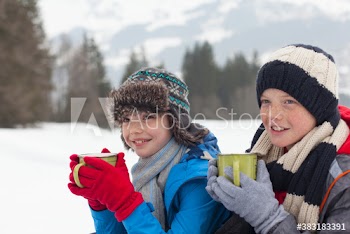 Smiling brothers drinking hot cocoa in snowy field
