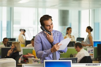 Smiling businessman talking on telephone in open plan office