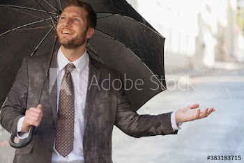 Smiling businessman with umbrella on rainy street