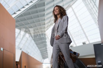 Smiling businesswoman pulling suitcase in airport