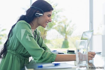 Smiling businesswoman with headset at laptop