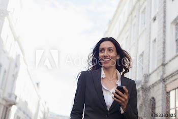 Smiling businesswoman with smart phone on city street
