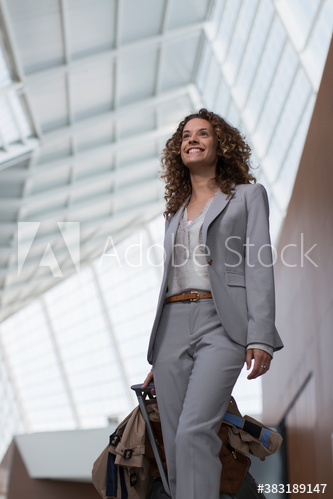 Smiling businesswoman with suitcase in airport