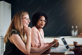 Smiling businesswomen talking with colleagues in an office boardroom