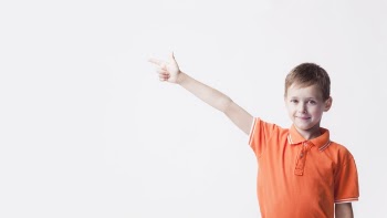 Smiling caucasian boy pointing index finger at side on white backdrop Free Photo