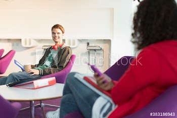 Smiling college students talking and studying in student lounge