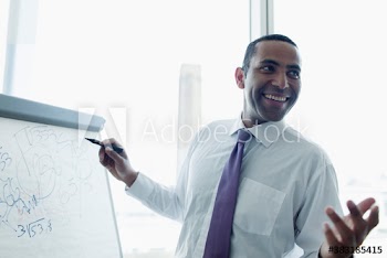 Smiling corporate businessman at flipchart in meeting