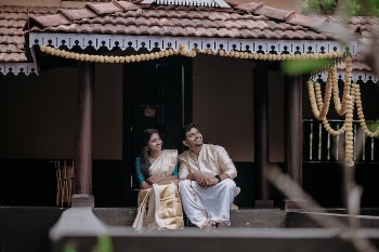Smiling Couple in Traditional Clothes Sitting on Stairs near House
