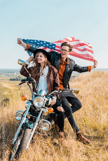 smiling couple with american flag sitting on motorbike, independence day concept
