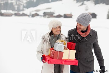 Smiling couple with Christmas gifts in snowy field