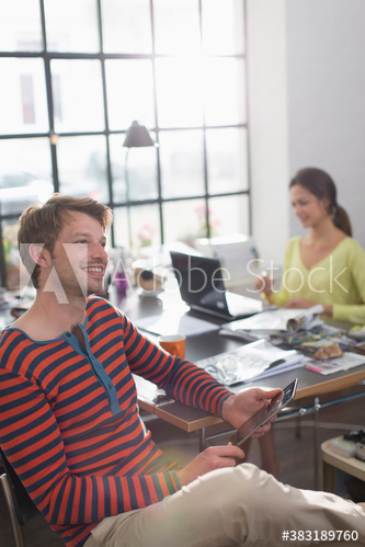 Smiling creative businessman with digital tablet in office