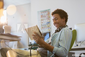 Smiling creative young businessman using digital tablet in office