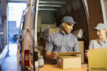 Smiling delivery people with boxes outside delivery van