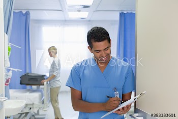 Smiling doctor with clipboard making rounds in hospital