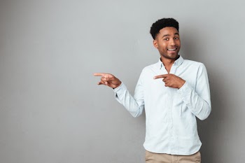 Smiling excited african man pointing finger away Free Photo