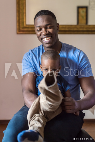 Smiling father dressing up his son at home
