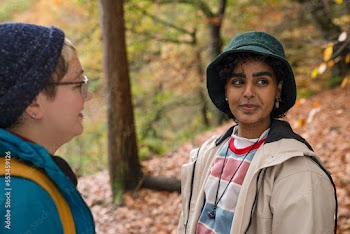 Smiling female friends hiking in forest