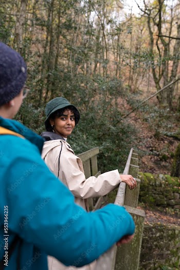 Smiling female hikers on bridge in forest