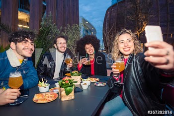 Smiling friends taking selfie while enjoying drinks at nightclub