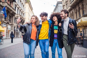 Smiling friends taking selfie while walking on street