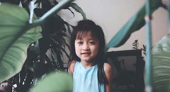 Smiling Girl Wearing Teal Tank Top Surrounded by Plants