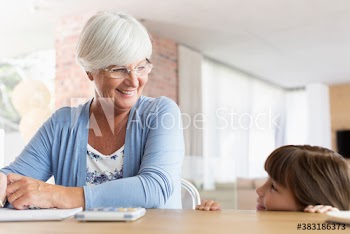 Smiling grandmother and granddaughter at dining table