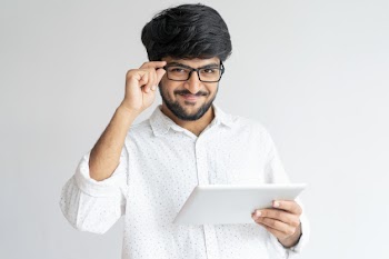 Smiling indian man using tablet computer and adjusting glasses