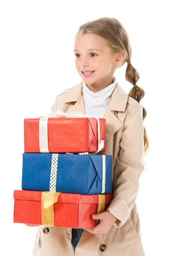 Smiling kid in beige coat holding gifts, isolated on white